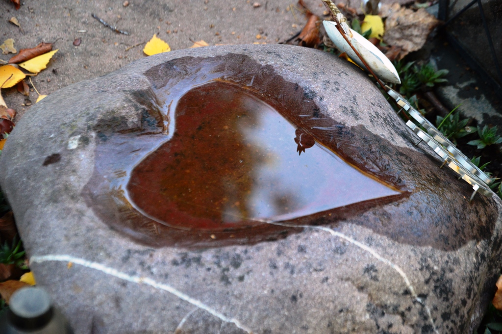 Ein Herz als Vogelbrunnen in einem Stein. Symbol für Kinderschutz.