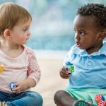 Zwei Kleinkinder die sich anschauen und nonverbal miteinander kommunizieren.