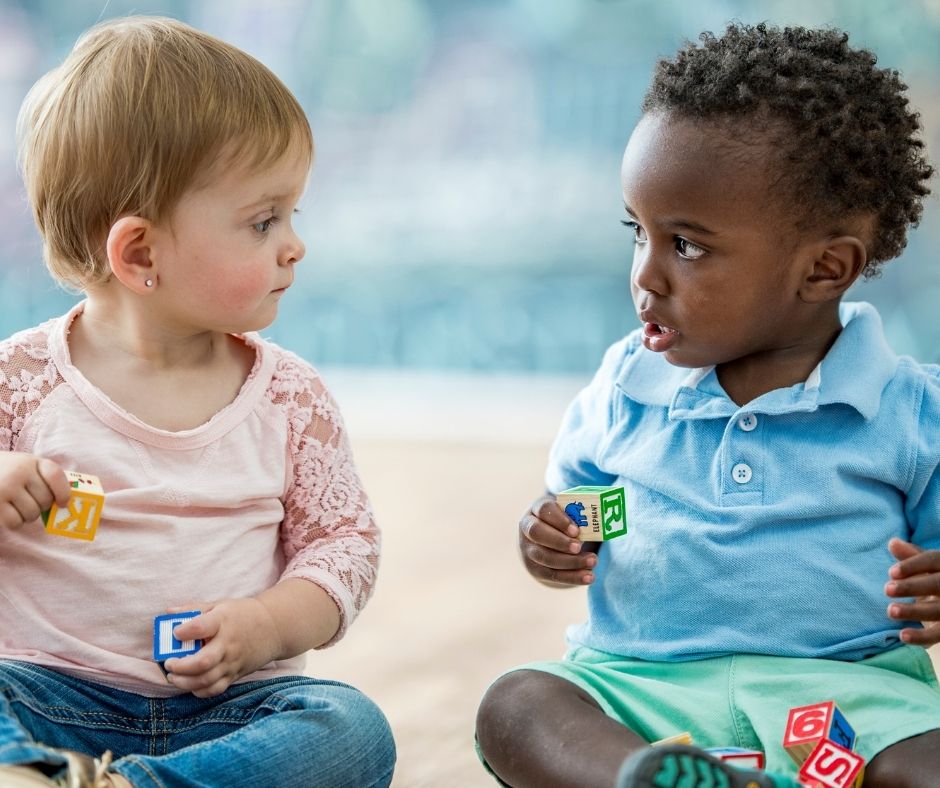 Zwei Kleinkinder die sich anschauen und nonverbal miteinander kommunizieren.